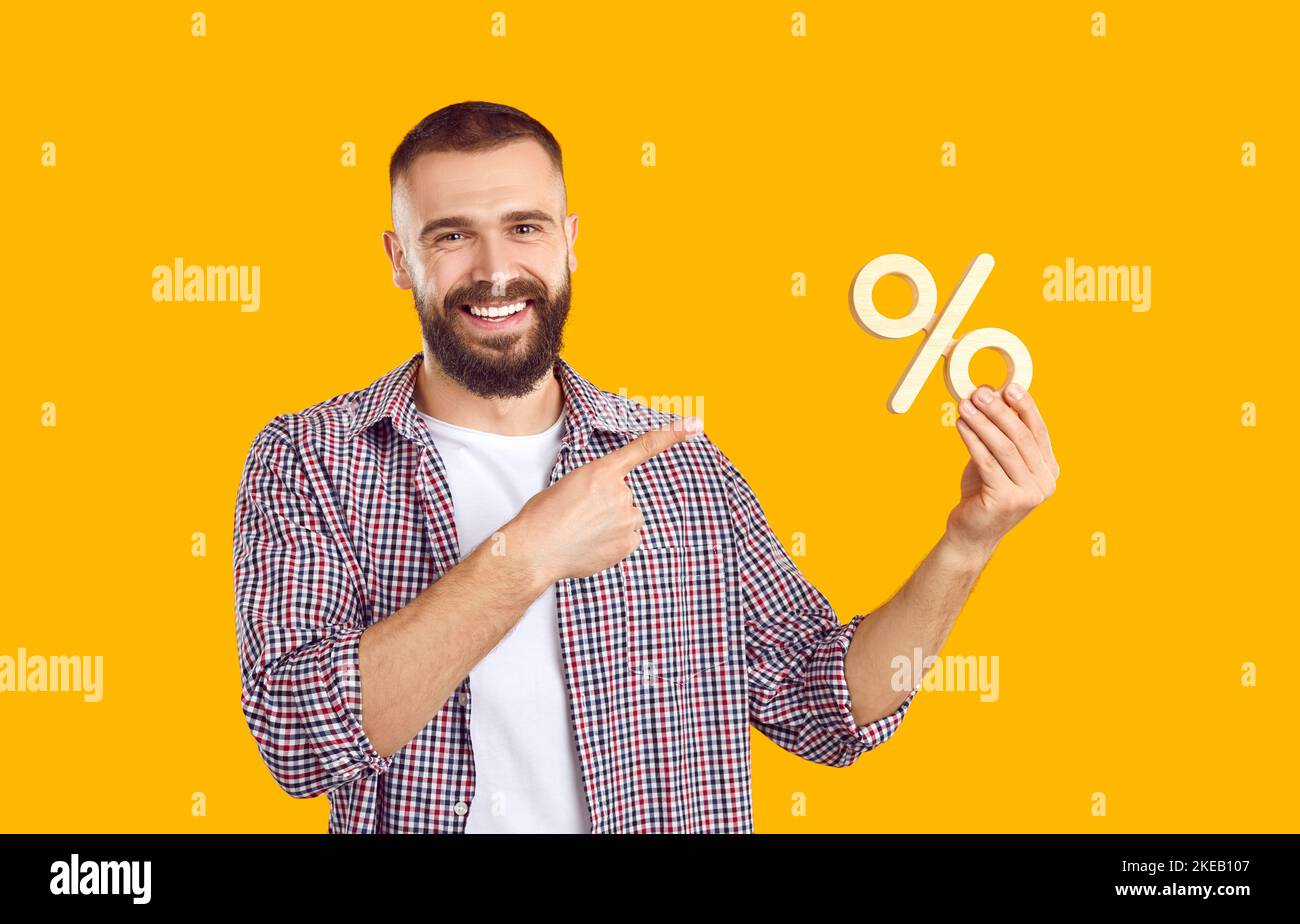 Ritratto di felice giovane uomo che fa pubblicità alla vendita e tenendo il simbolo della percentuale di sconto Foto Stock