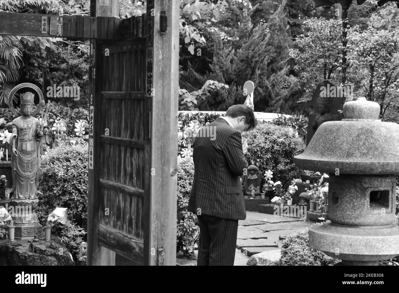 Un'immagine monocromatica di un uomo che prega in un tempio, Tokyo, Giappone Foto Stock