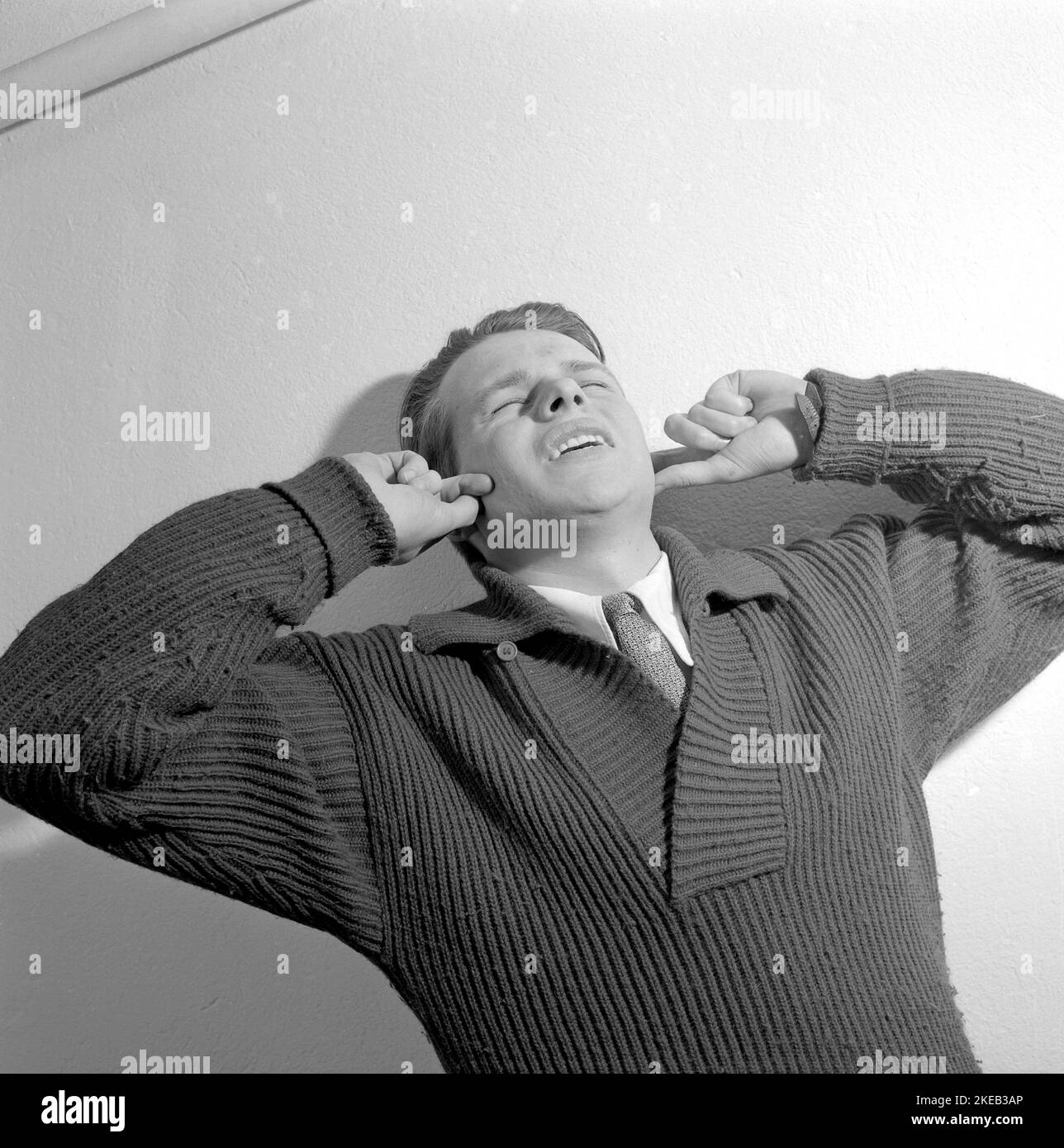 Negli anni '1950s. Un giovane uomo tiene le mani sopra le orecchie e ha un'espressione facciale che indica che potrebbe essere sensibile al suono, disturbi dell'udito, depressione, mal di testa o malattia psichiatrica. Svezia 1956. Rif. Conard 3190 Foto Stock
