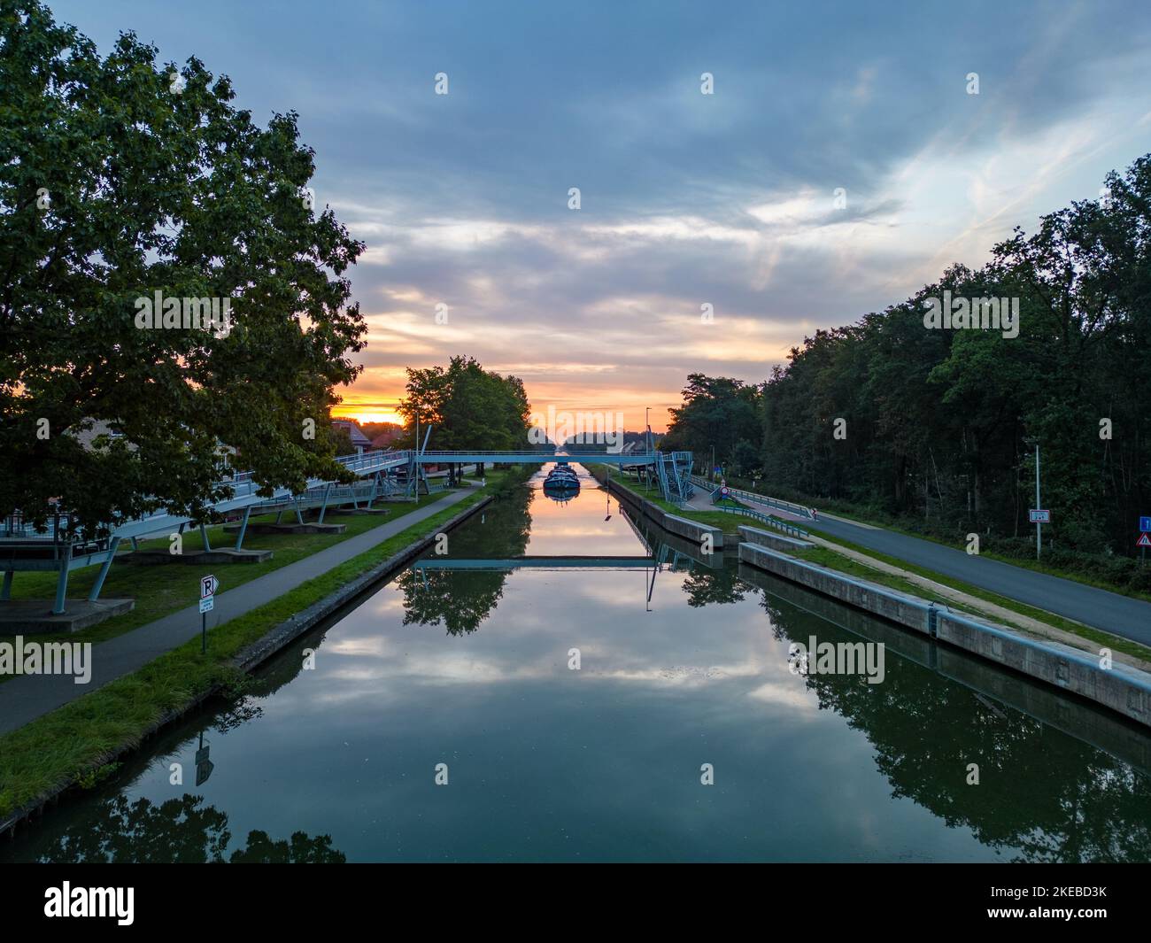 Vista aerea di un colorato e suggestivo cielo all'alba su un canale con una barca da carico in Belgio. Canali con acqua per i trasporti, l'agricoltura. Campi e prati. Vista aerea panoramica ripresa da un drone. Foto di alta qualità Foto Stock