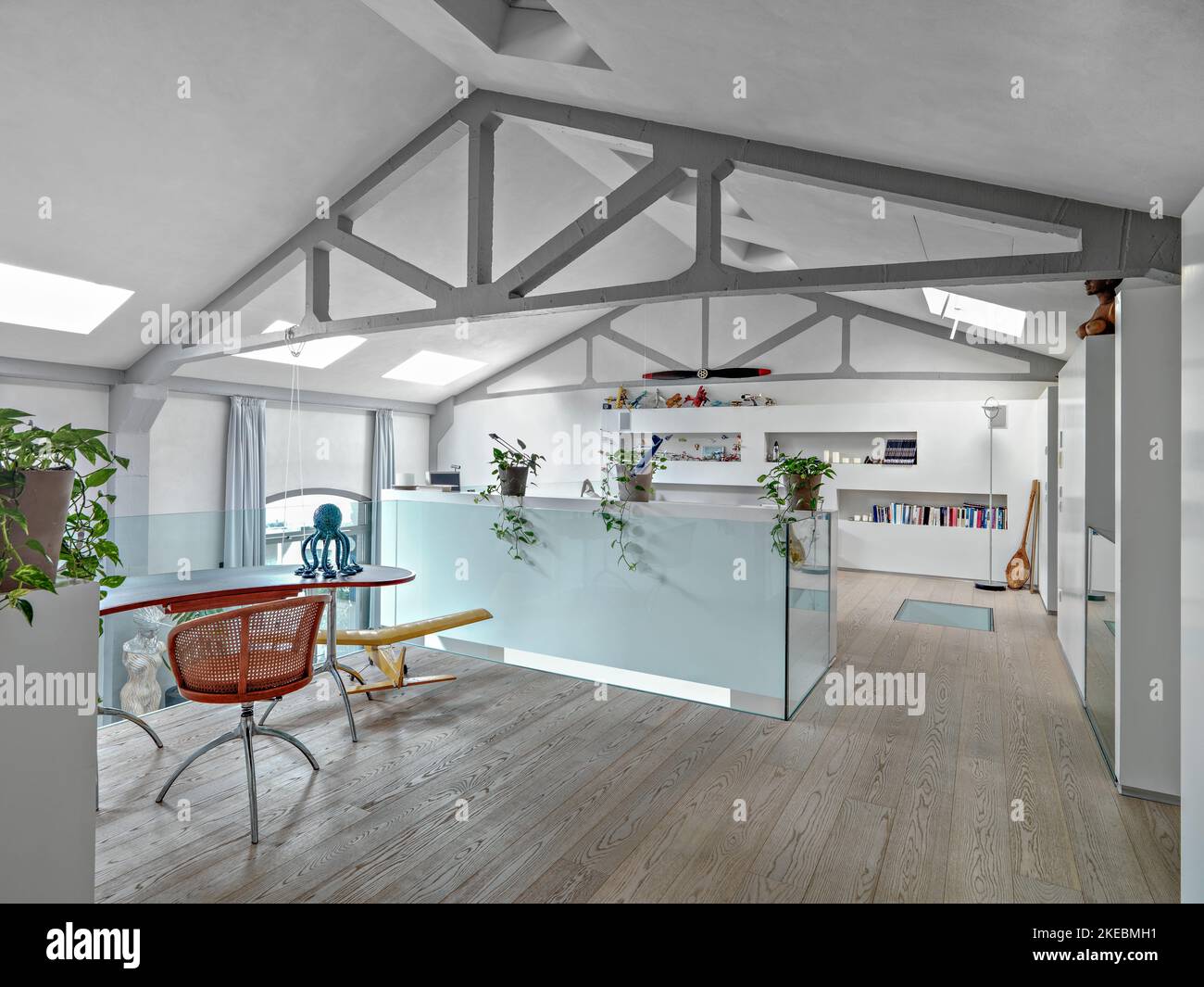 immagini interne di un moderno soggiorno nella camera mansardata in primo piano la scrivania con pavimento in legno Foto Stock