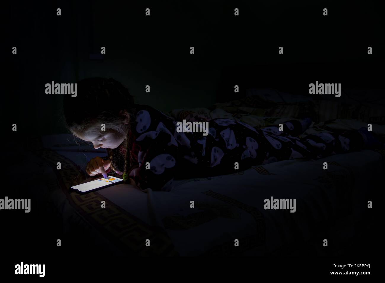 Una ragazza con un telefono cellulare sul letto. Foto Stock