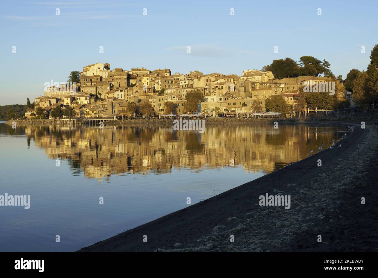 Il centro storico di Anguillara Sabazia, si riflette nel lago di Bracciano, illuminato dalla luce del tramonto Foto Stock