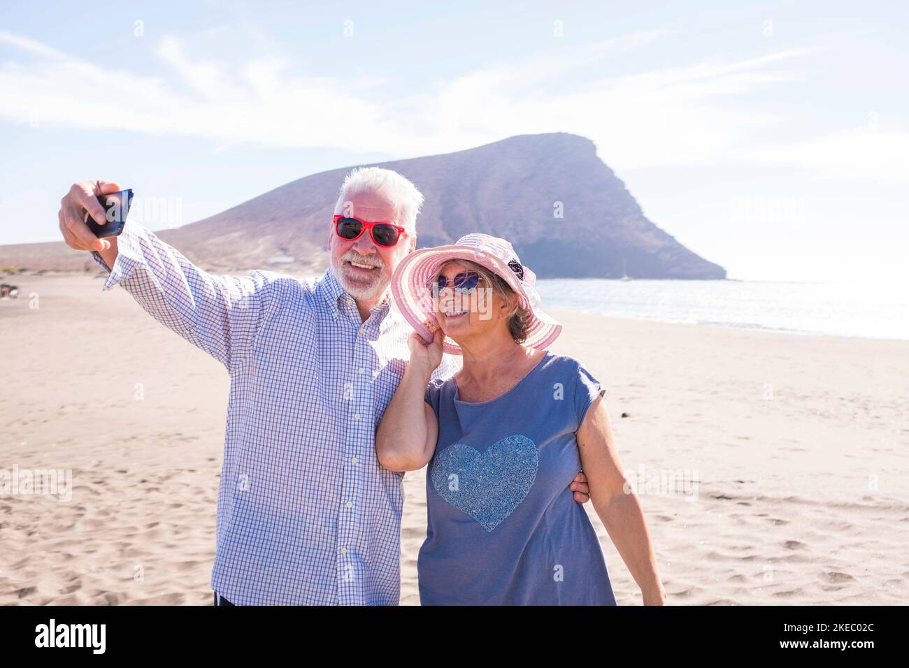 due persone mature che prendono un selfie sulla spiaggia sorridendo e divertendosi - anziani o pensionati godendo le loro vacanze o vacanze all'aperto - giorno di sole in spiaggia Foto Stock