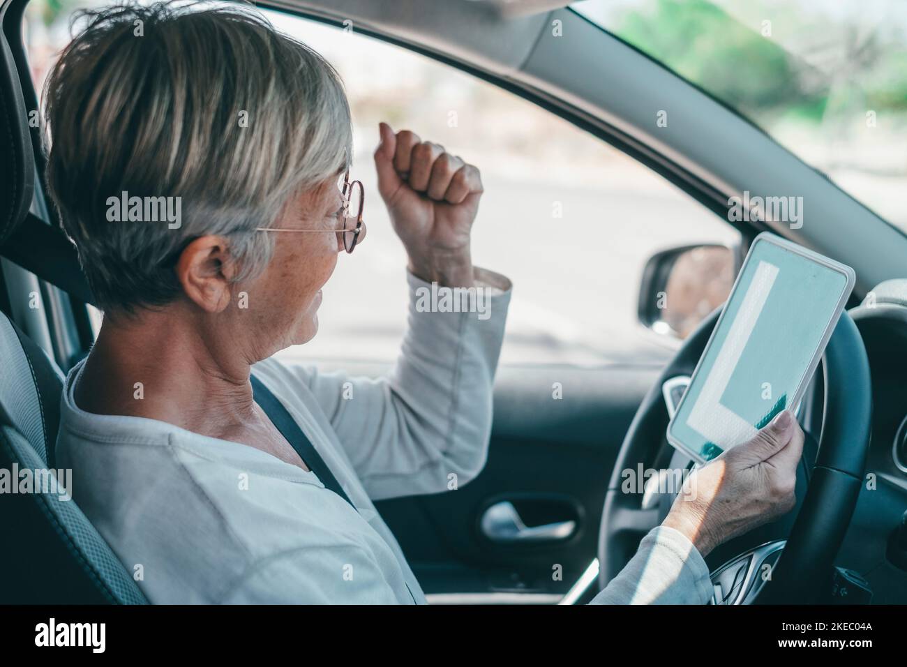 Una donna anziana ottiene il pass per guidare un'auto in età matura. Senior guardando al permesso L nel sedile di guida per celebrare il successo Foto Stock