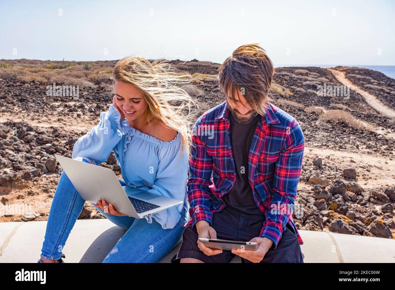 coppia di due adulti che usano il laptop e l'ipad insieme all'esterno - concetto di tecnologia e stile di vita online - bella donna e. bell'uomo che si diverte insieme Foto Stock