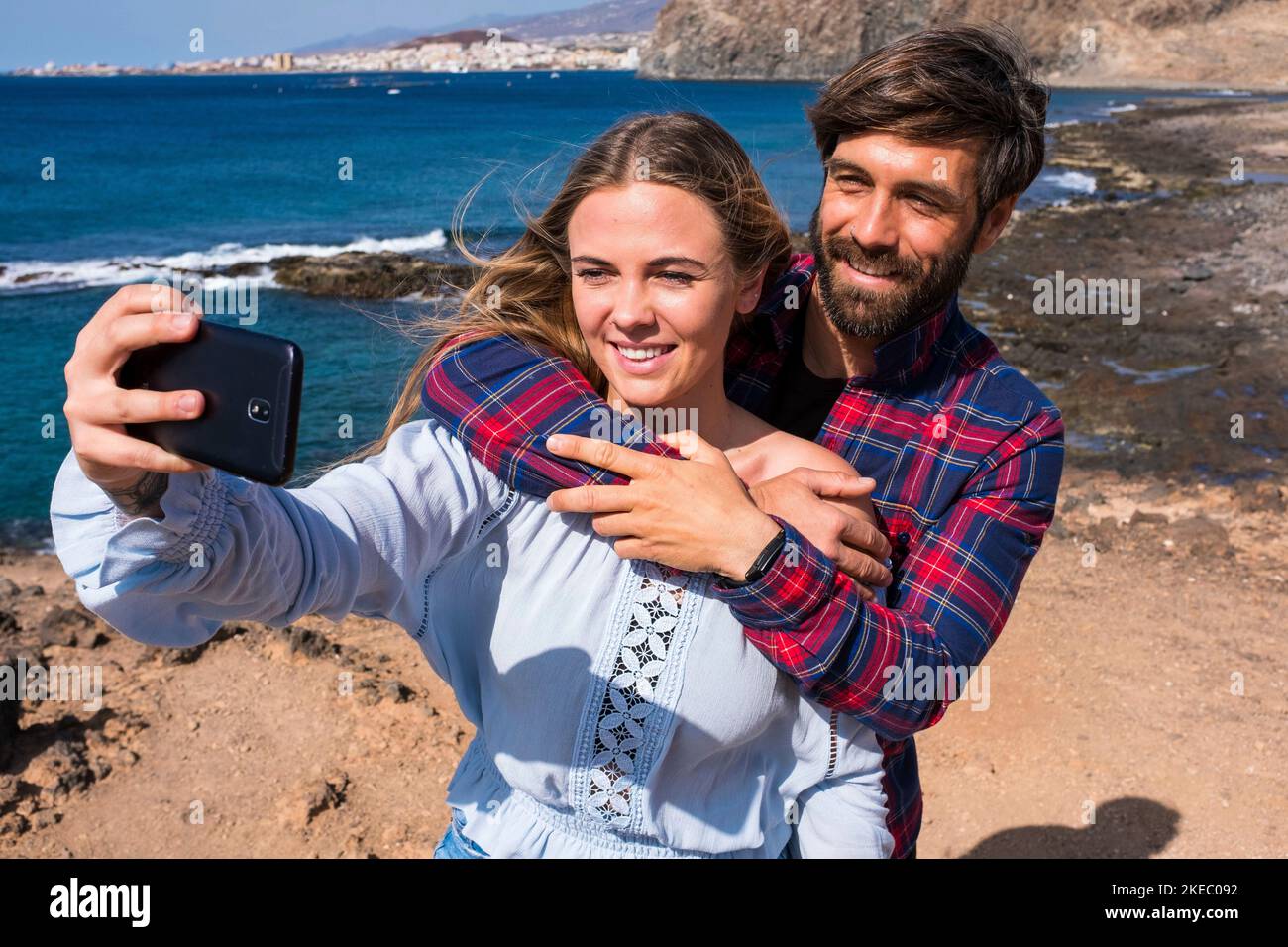 carino coppia di adulti che prendono un selfie insieme un spiaggia con il mare sullo sfondo - due belle e le persone attraenti sorridendo guardando la fotocamera Foto Stock