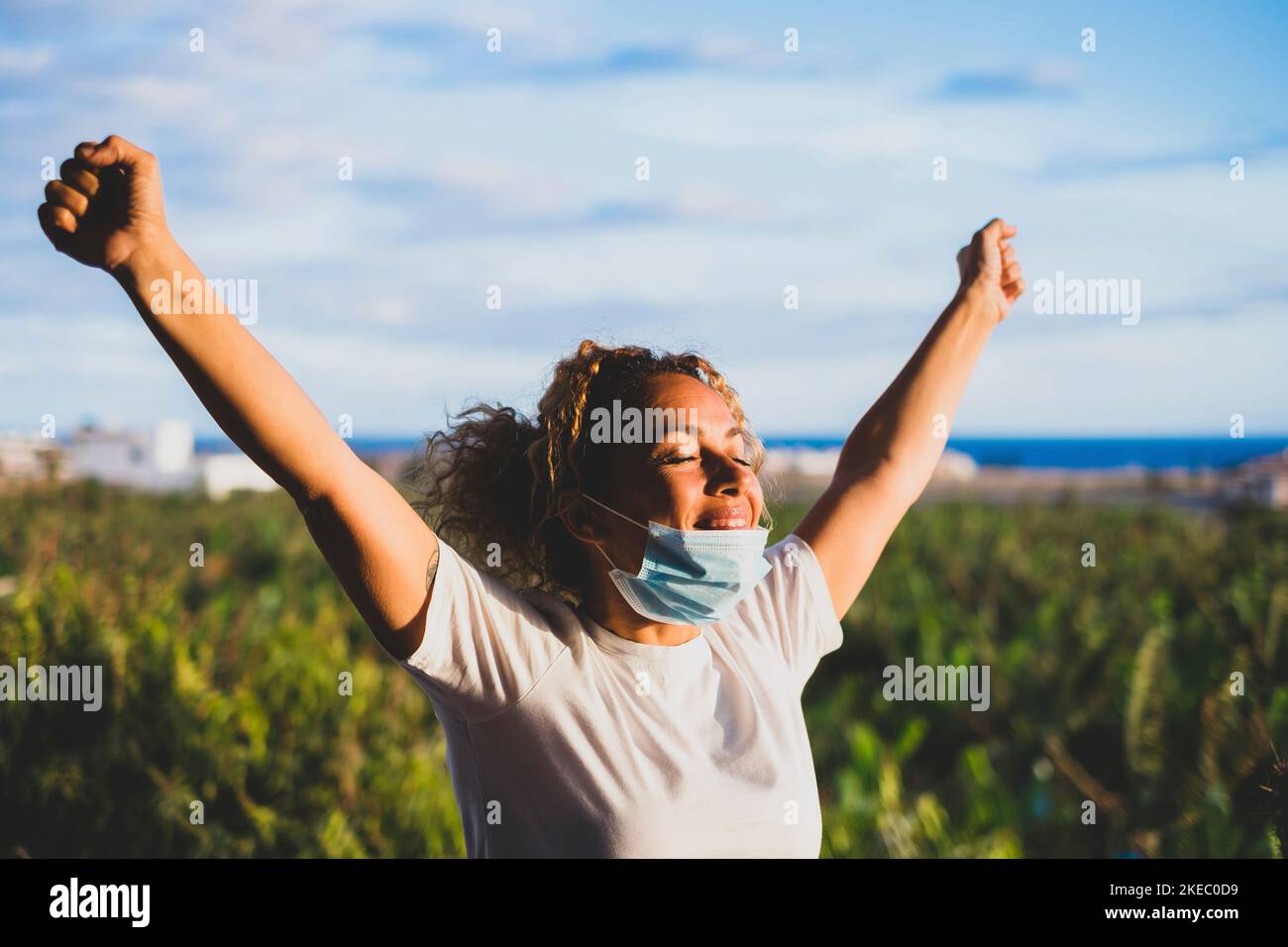 donna che indossa una maschera sorridente e guarda la fotocamera per celebrare la fine del covid-19 Foto Stock