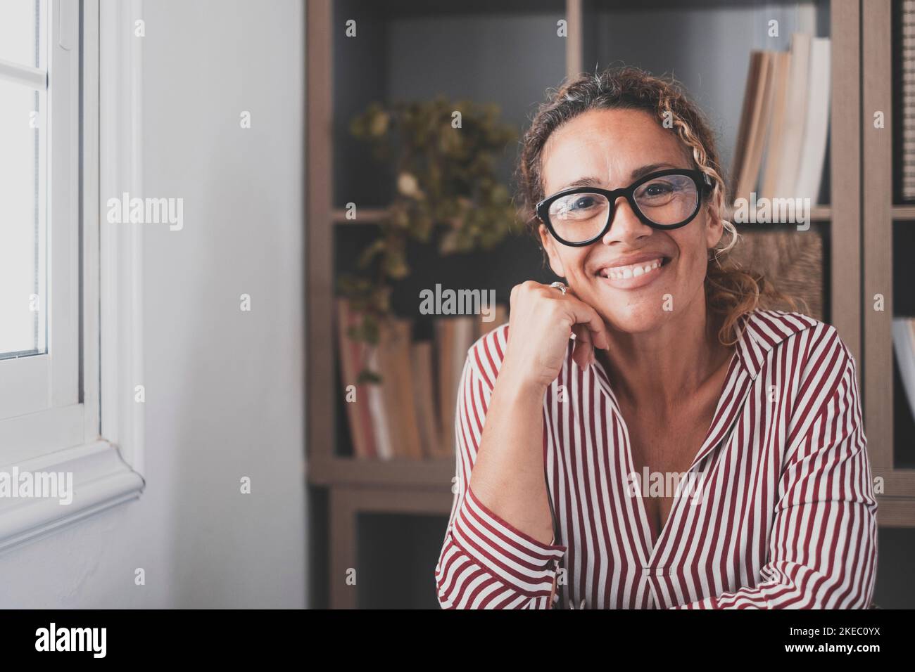Ritratto di una giovane e felice donna allegra sorridente guardando la macchina fotografica divertirsi. Colpo di testa di donna che lavora a casa in ufficio. Foto Stock