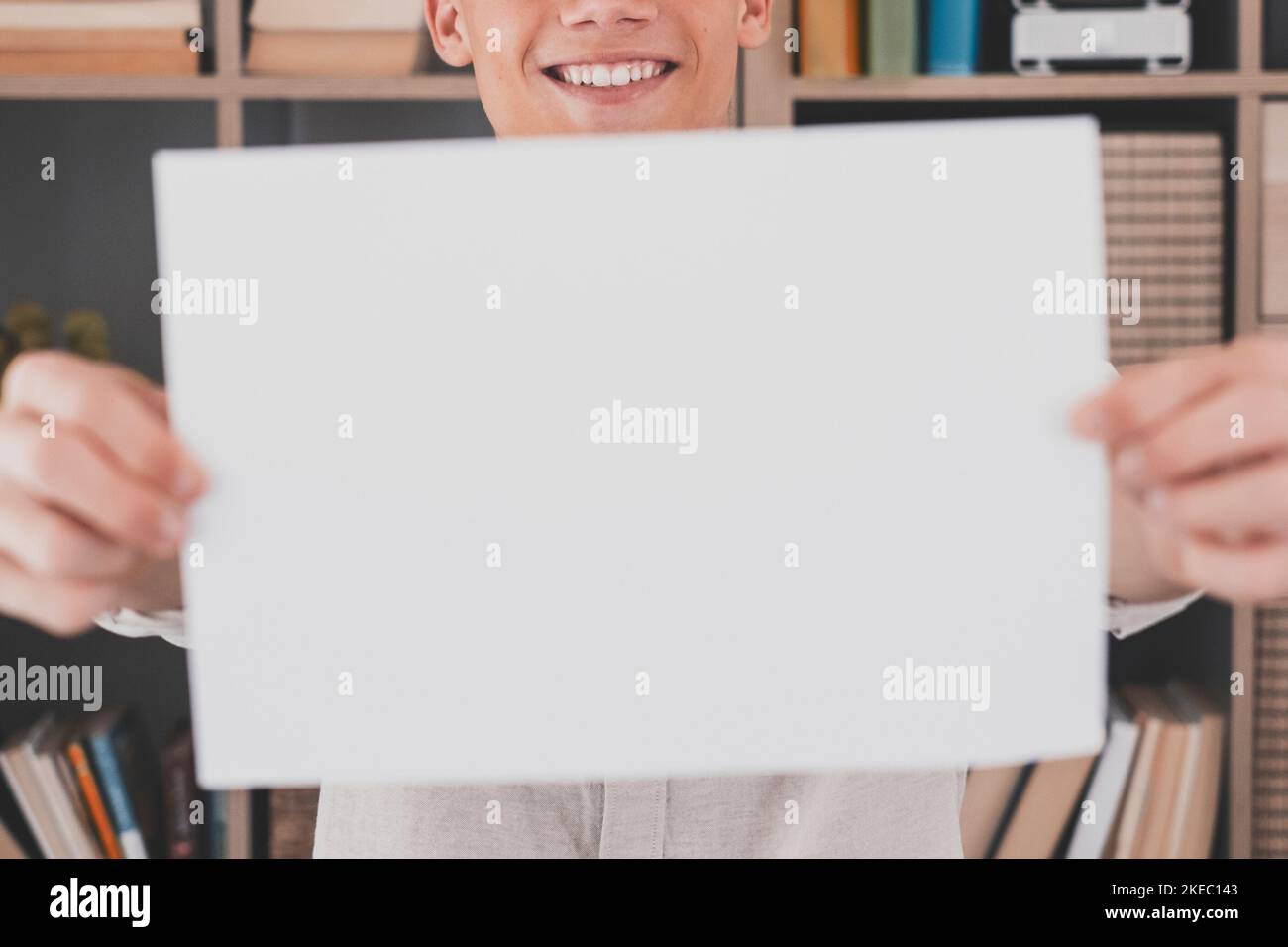 Primo piano concentrarsi su un uomo che tiene bianco foglio per copiare spazio. Sorridente giovane giovane uomo caucasico giovane attraente che consiglia un buon servizio, soddisfatto con successo di carriera in azienda internazionale. Foto Stock
