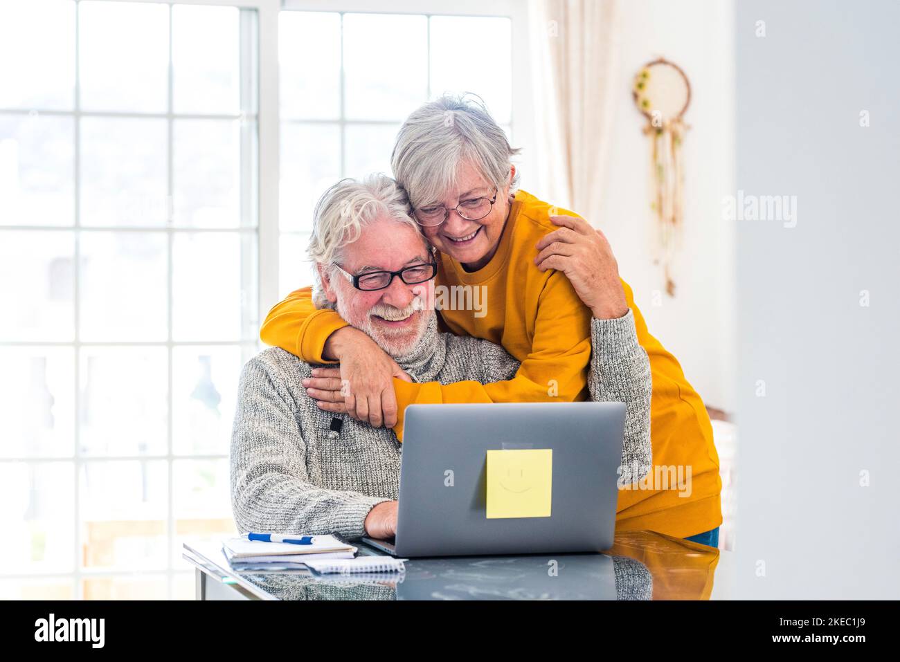 coppia di due anziani felici che lavorano e usano un computer portatile insieme a casa sorridendo e divertendosi insieme: stile di vita chiuso Foto Stock