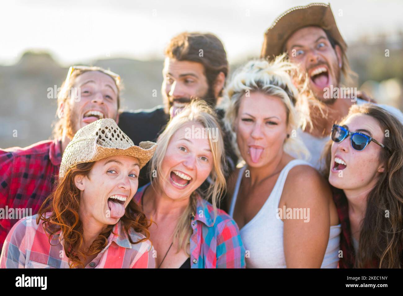 gruppo di sette persone che guardano insieme la fotocamera espressioni dei volti pazzi e divertenti - caucasici divertenti e felici gente - cowboy e cowgirl in un ranch che si diverte godendo Foto Stock