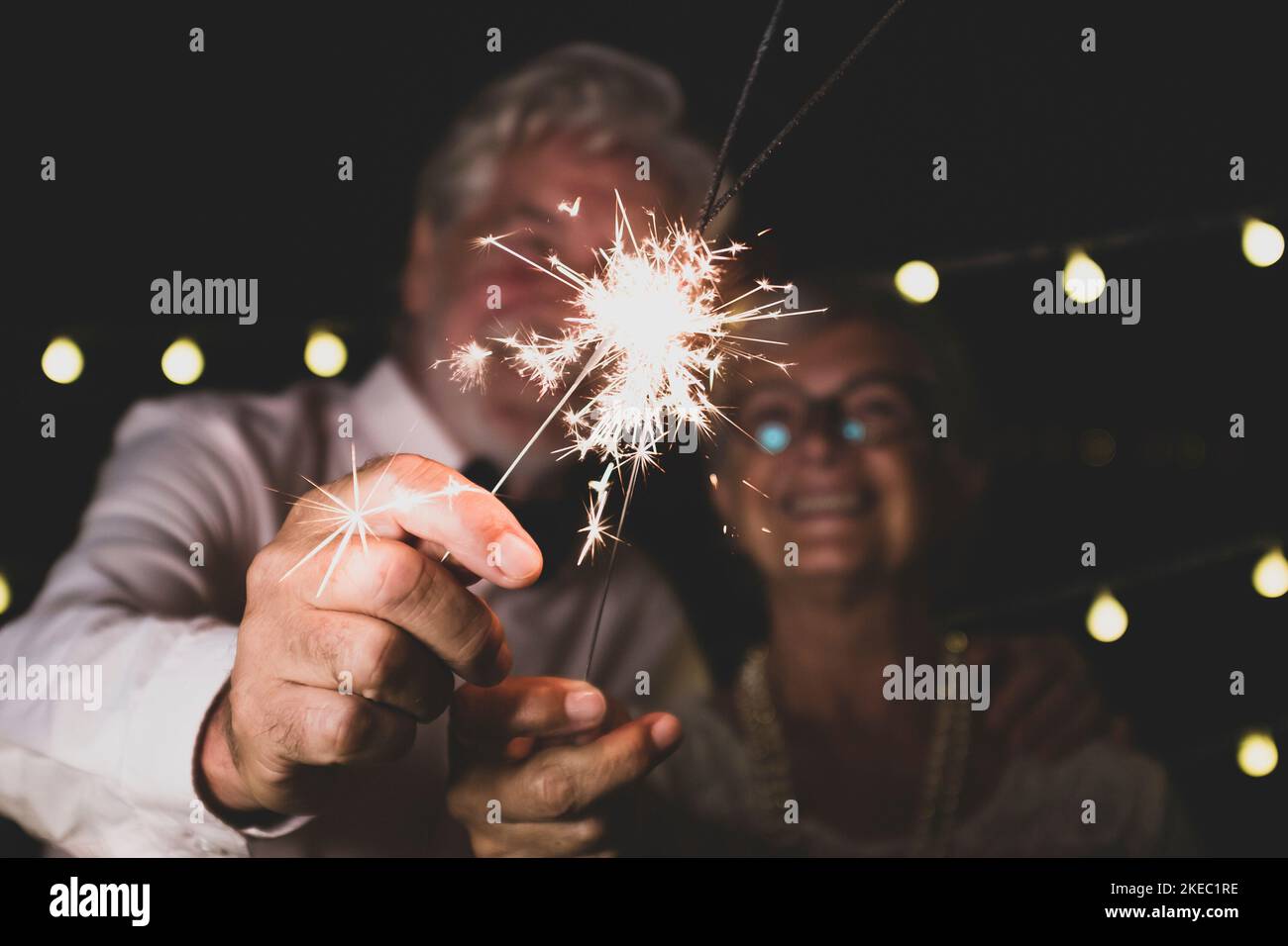 carino coppia di due anziani in amore insieme il nuovo notte di anno giocando con gli sparklers nella loro mano vicino della fotocamera Foto Stock
