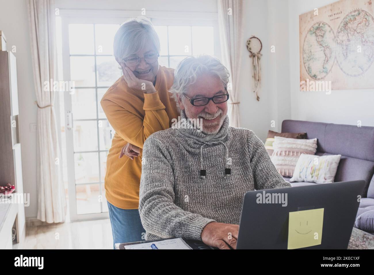 coppia di due anziani felici che lavorano e usano un computer portatile insieme a casa sorridendo e divertendosi insieme: stile di vita chiuso Foto Stock