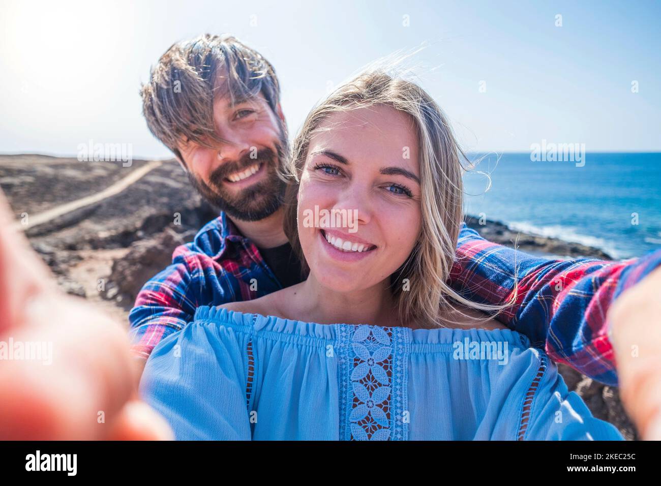 coppia di adulti e fidanzati che prendono un selfie insieme con le loro quattro mani - due persone innamorate che tengono il telefono con la spiaggia sullo sfondo Foto Stock