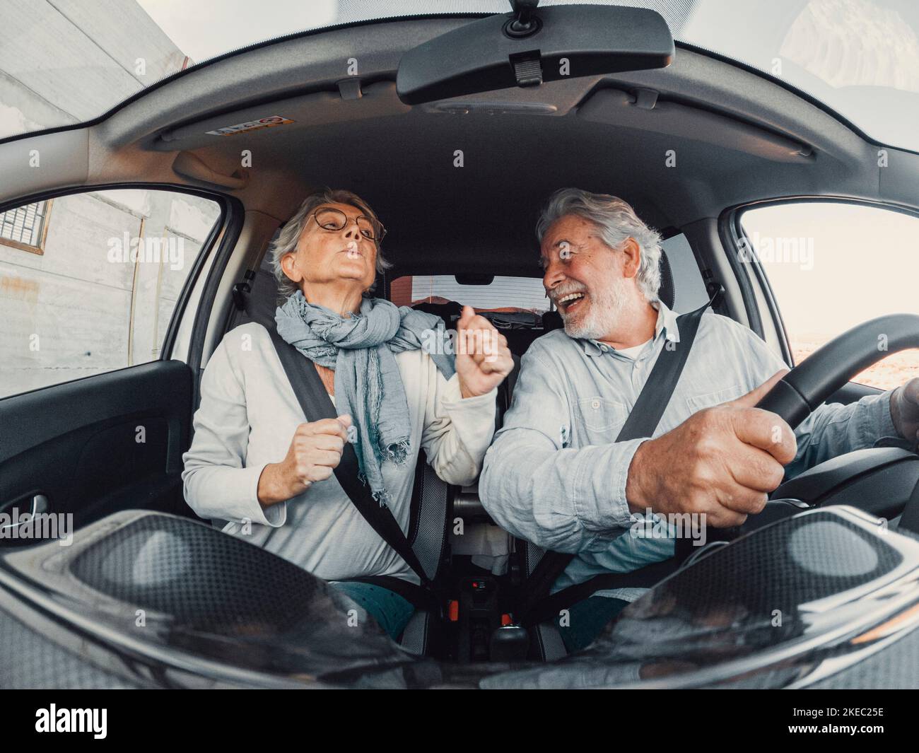 Coppia di due felici danzanti anziani che cantano in vacanza insieme alla guida e alla scoperta di nuovi posti con una macchina. Foto Stock