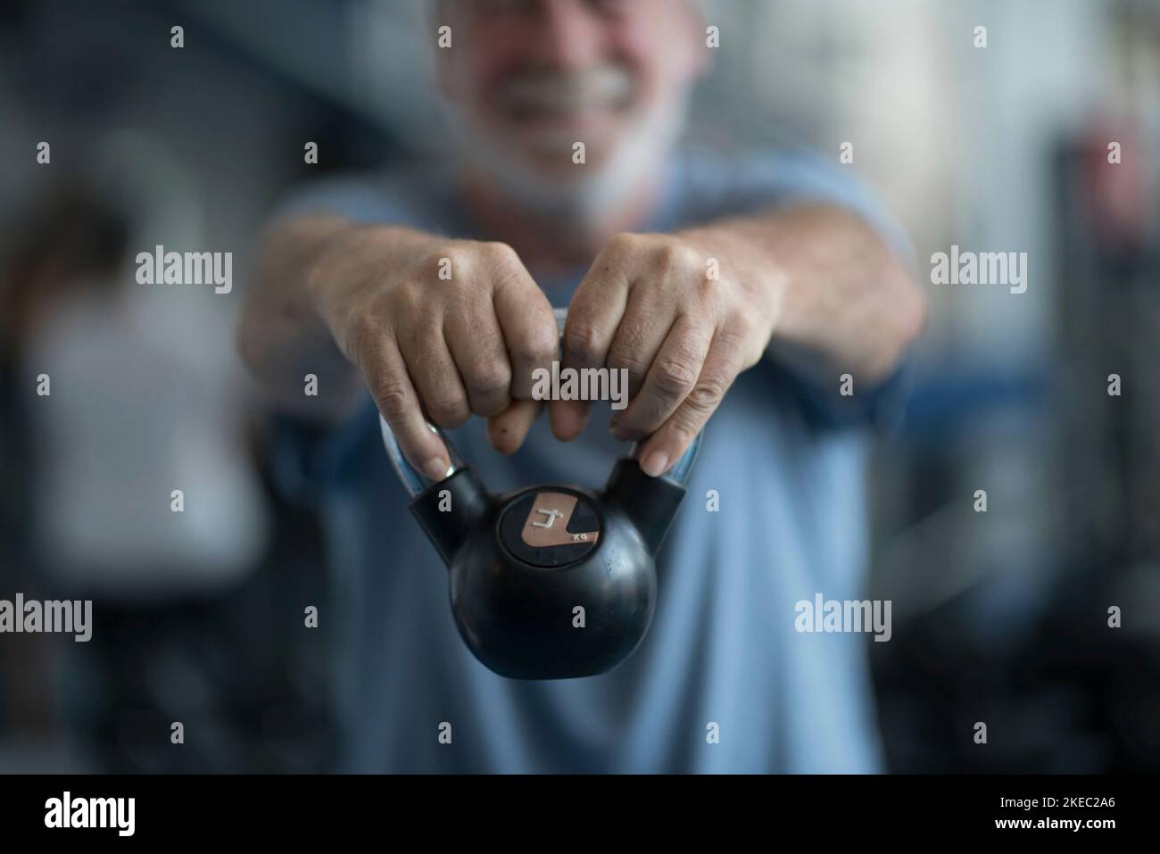 un uomo maturo che tiene un peso alla palestra facendo esercizio per essere sano e fitness - senior in un palestra che fa attività Foto Stock