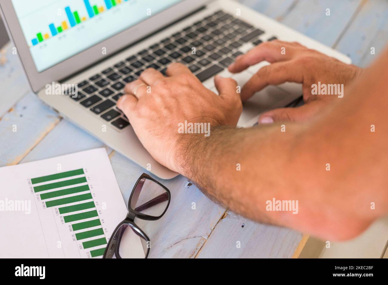 primo piano di battitura di mani e braccia con un computer portatile e statistics - grafici sul tavolo - lavoro e. guardando i grafici Foto Stock