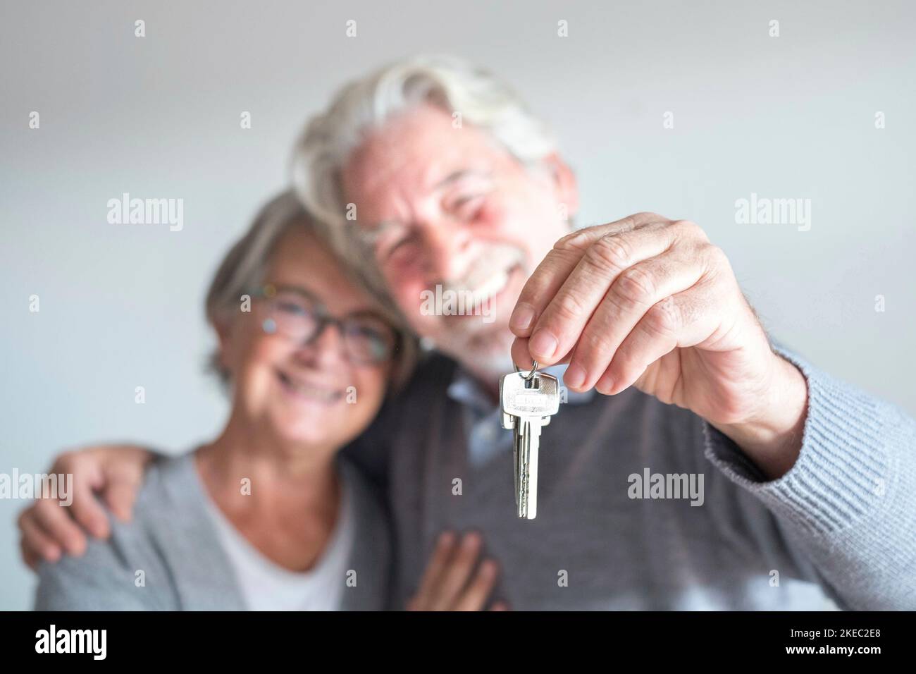 coppia di due anziani dopo l'acquisto di una nuova casa o auto e andare a vivere insieme - uomo che tiene una chiave e maturo uomo e donna che lo guarda Foto Stock