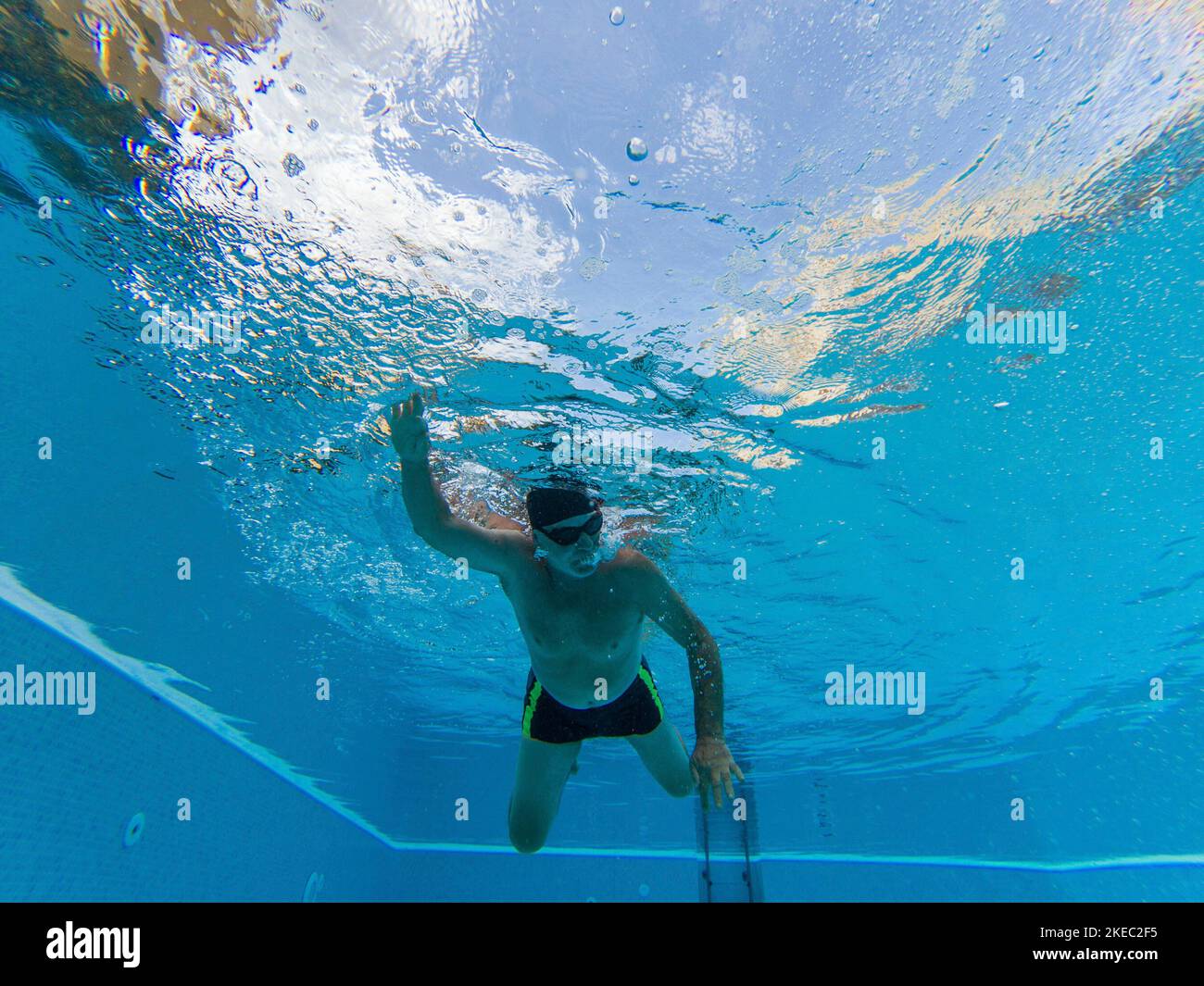 un uomo maturo o anziano che si allenano e che fanno il nuoto in una piscina da solo - sotto la vista dell'acqua del nuoto pensionato - uno stile di vita attivo anziano e sano Foto Stock