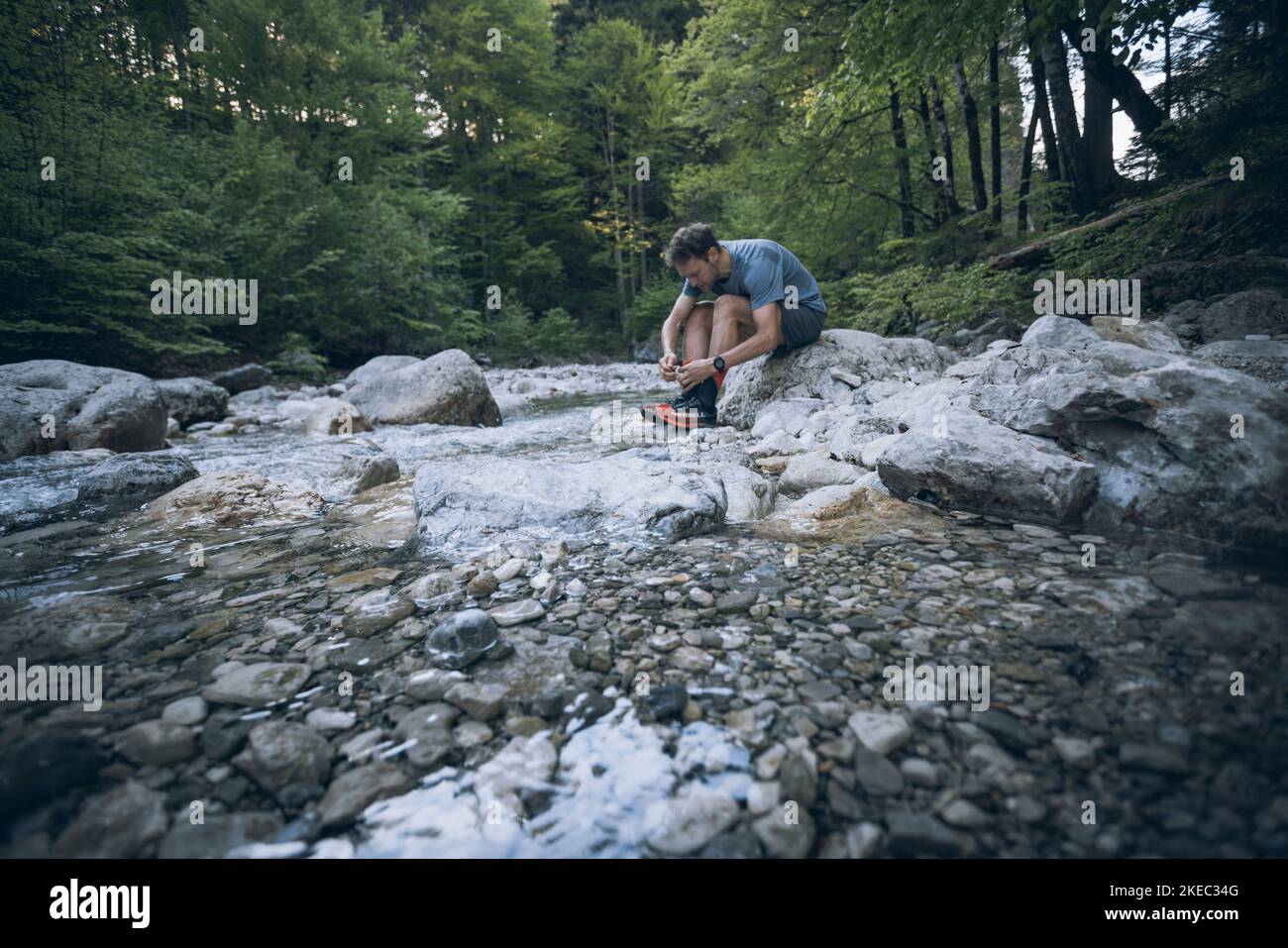 Uomo sportivo in letto di fiume che lega le scarpe sportive Foto Stock