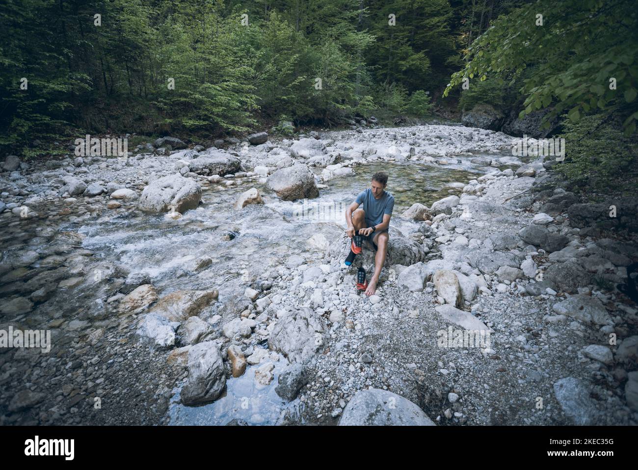 Uomo sportivo in letto di fiume che lega le scarpe sportive Foto Stock