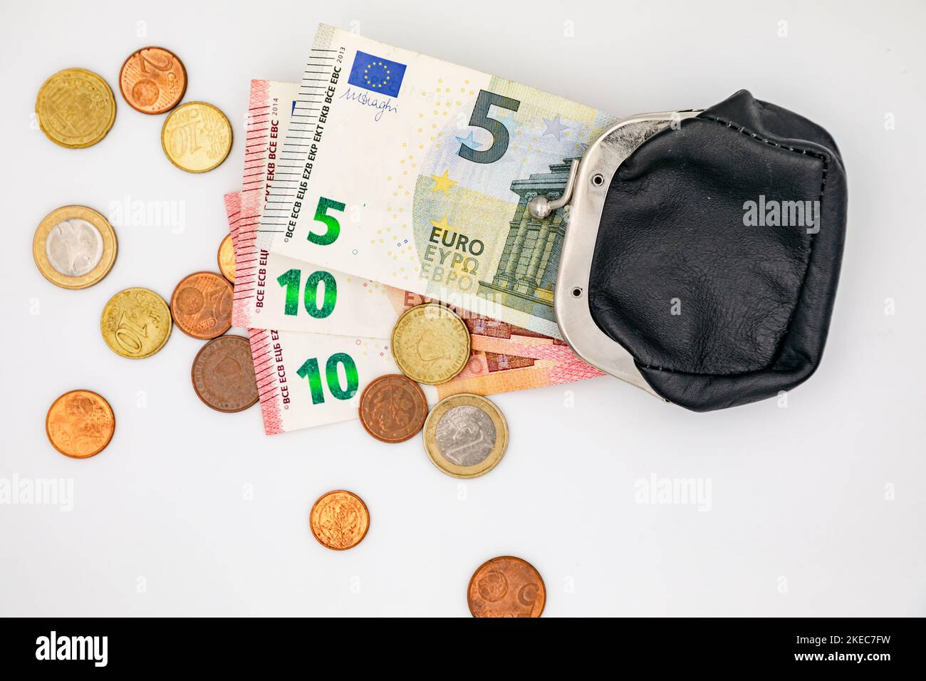 Un piccolo cambio di monete e banconote in euro e un piccolo portamonete come segno di povertà Foto Stock