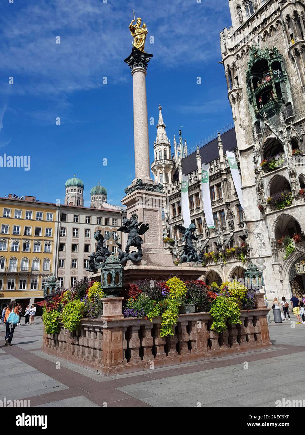 Marienplatz, centro della città. Colonna mariana al centro della piazza, dedicata a Santa Maria, come Patrona di Baviera. La colonna è coronata da una figura di Maria (Hubert Gerhard intorno al 1593). Il piedistallo commemora le quattro piaghe: Eresia (serpente), guerra (leone), fame (drago), peste (basilisk). Nella torre del municipio si trova lo storico carillon, da non perdere per ogni visitatore. Foto Stock