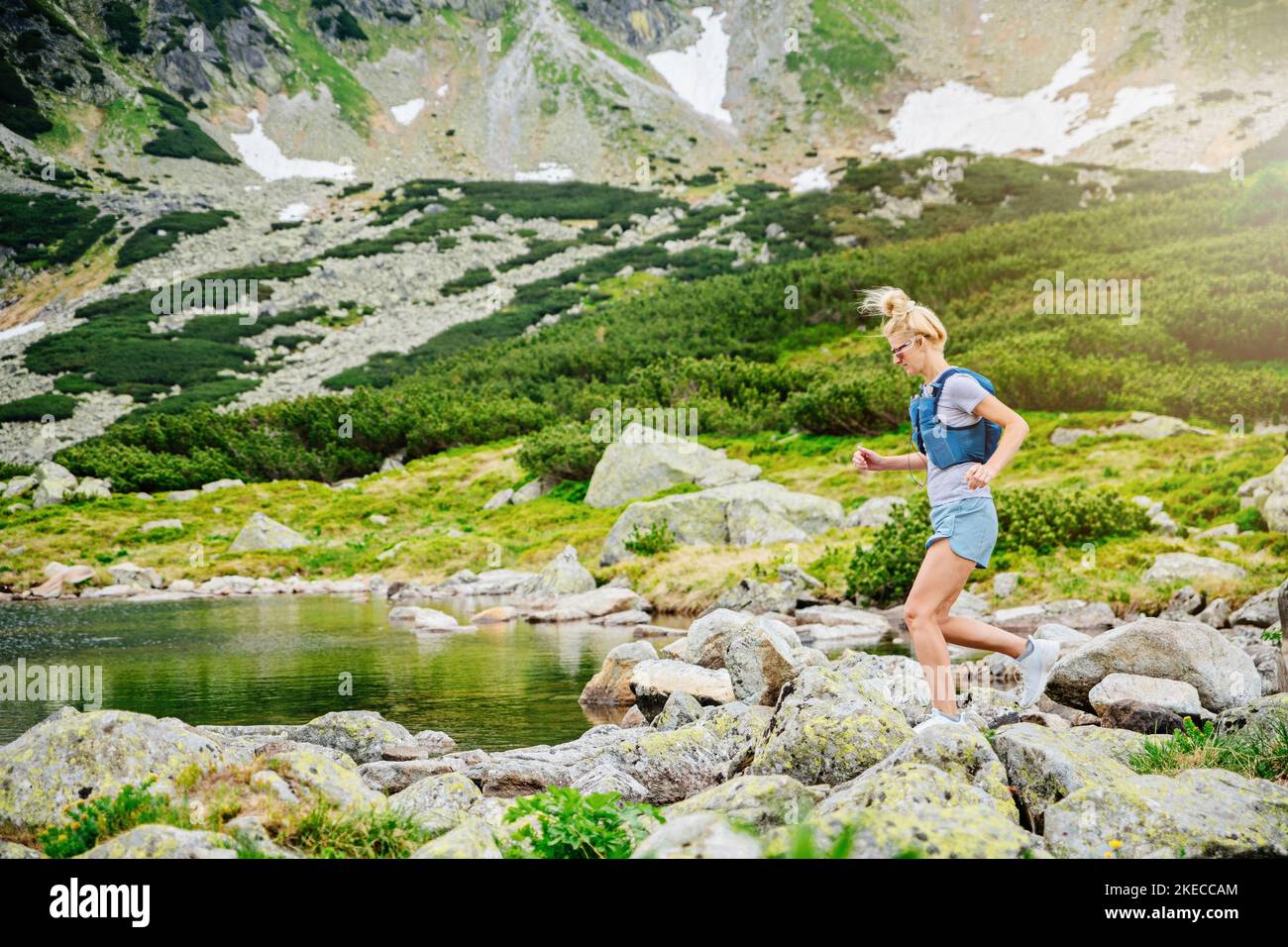 Donna bionda corre nei Tatra polacchi vicino al rifugio Stawow 5. Foto Stock