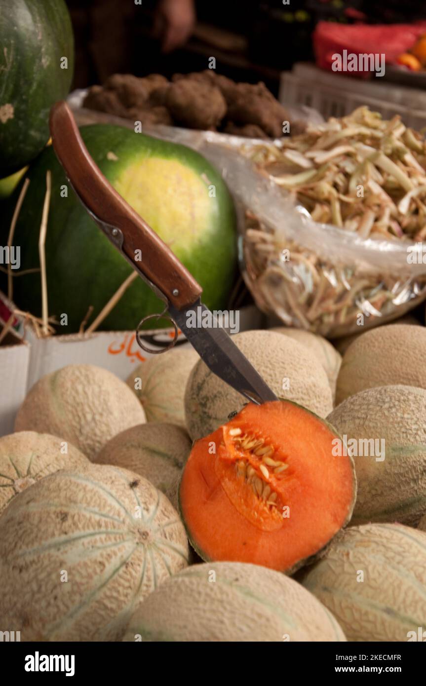 Meloni, cibo Stall, suk Tripoli, Tripoli, Libano. Un melone aperto per la degustazione con coltello pronto Foto Stock