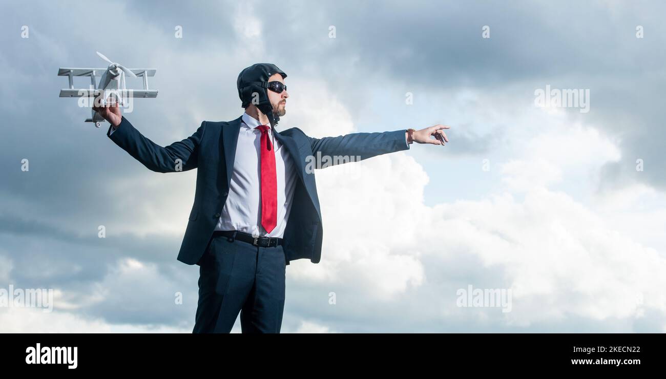 uomo d'affari maturo in tuta e cappello pilota lancio aereo giocattolo su sfondo cielo Foto Stock