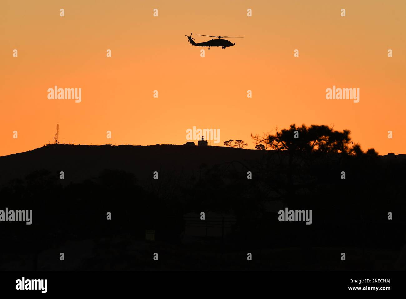 L'elicottero MH-60 della Marina degli Stati Uniti vola vicino al Cabrillo National Monument a San Diego, California al tramonto, come si vede da Coronado, California Foto Stock