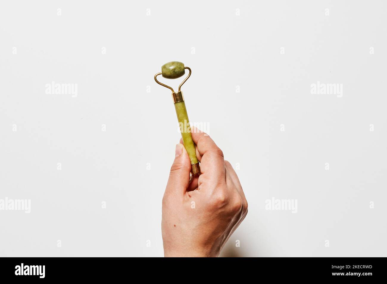 una mano che tiene una banana verde che è stata sbucciata a metà per renderla simile ad una mela Foto Stock