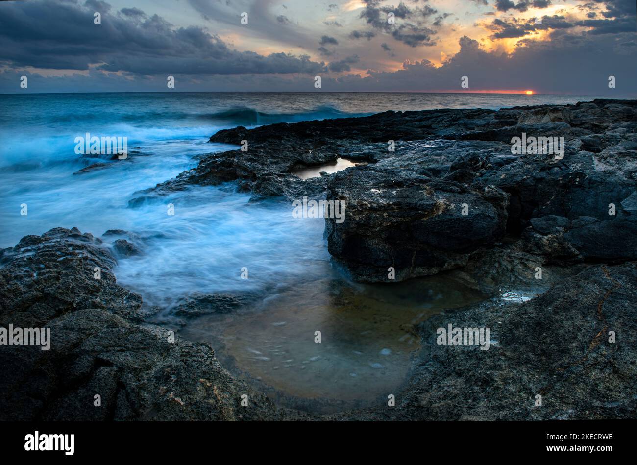 Mari accidentati sulla costa siciliana al tramonto Foto Stock