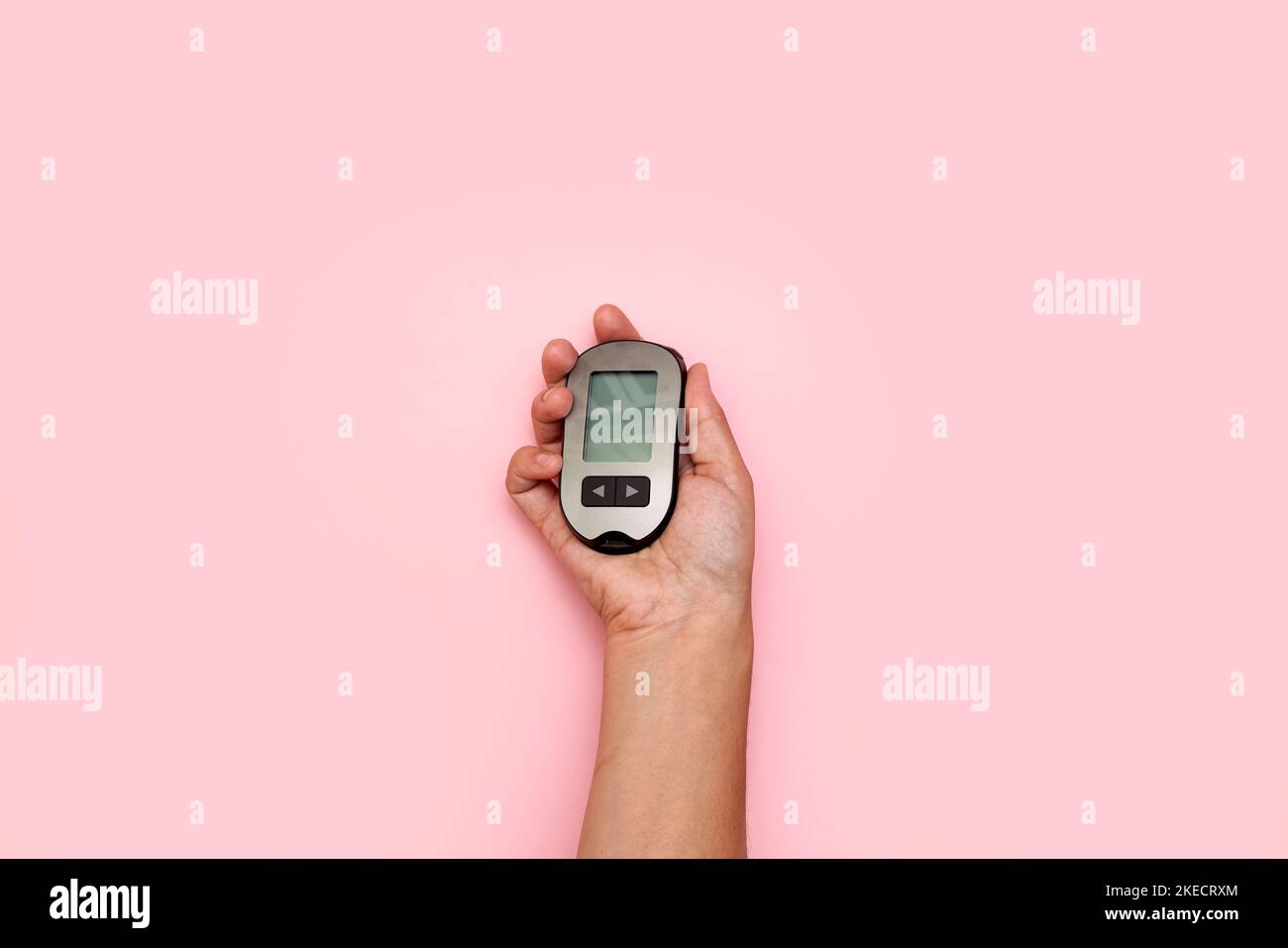 una mano di qualcuno che tiene un vecchio telefono cellulare su uno sfondo rosa con spazio copia nell'angolo in alto a sinistra Foto Stock