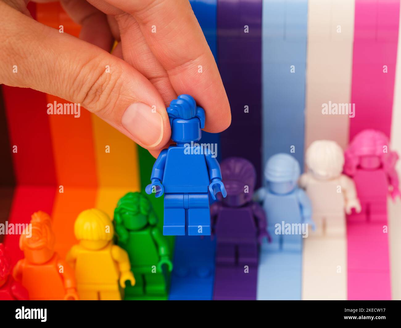 Tambov, Federazione Russa - 09 novembre 2022 Una mano donna che tiene una figura blu Lego sopra altre figure arcobaleno. LEGO tutti sono fantastici Foto Stock