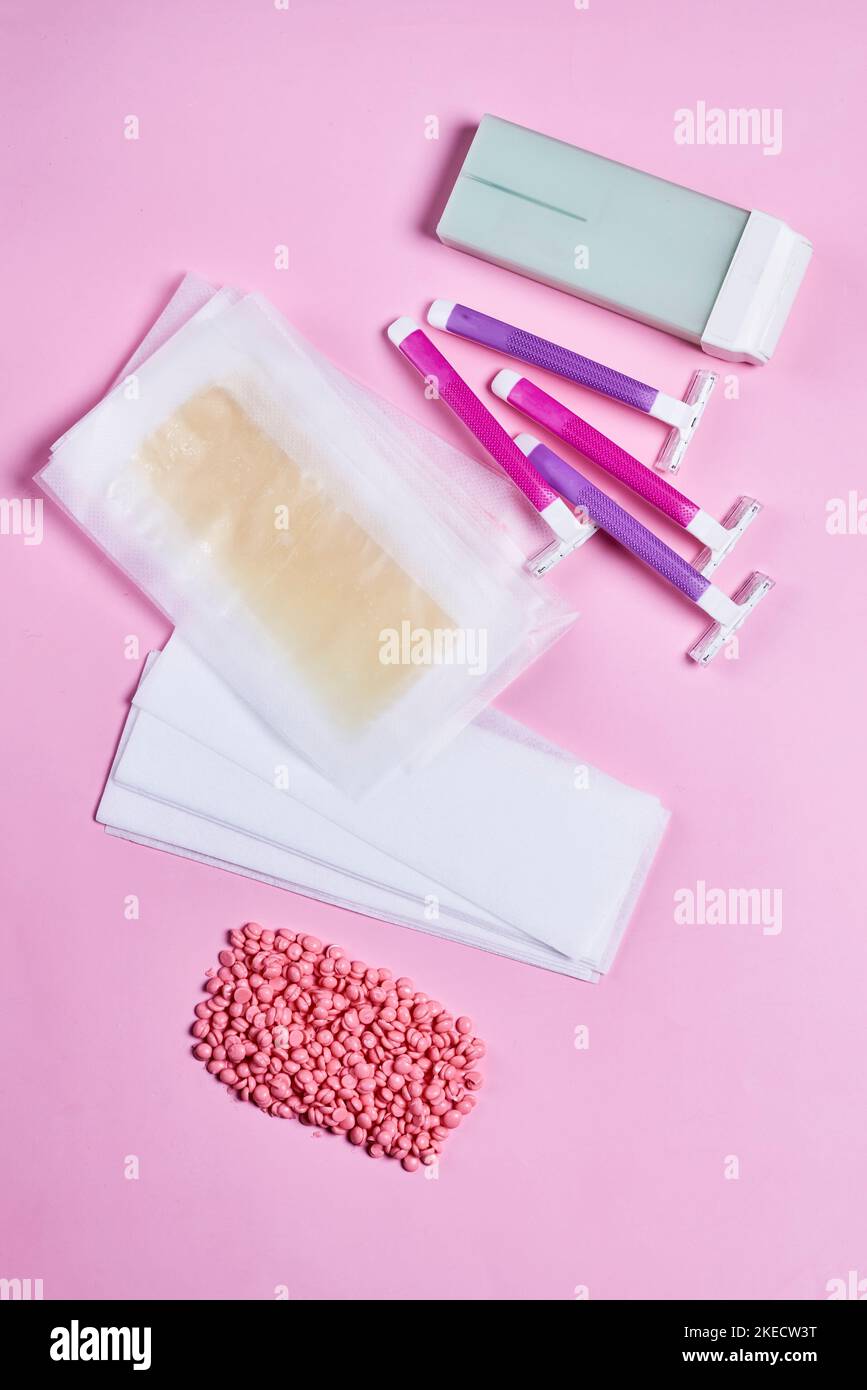 il contenuto di un kit display su sfondo rosa con pillole, dentifricio e un dispositivo elettronico Foto Stock