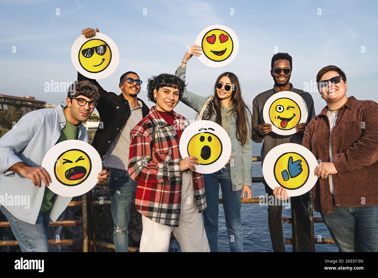 Gruppo di amici felici e positivi in possesso di dischi con emotoji disegnati a mano smiley volti in piedi all'aperto guardando la fotocamera - social network marketing tè Foto Stock