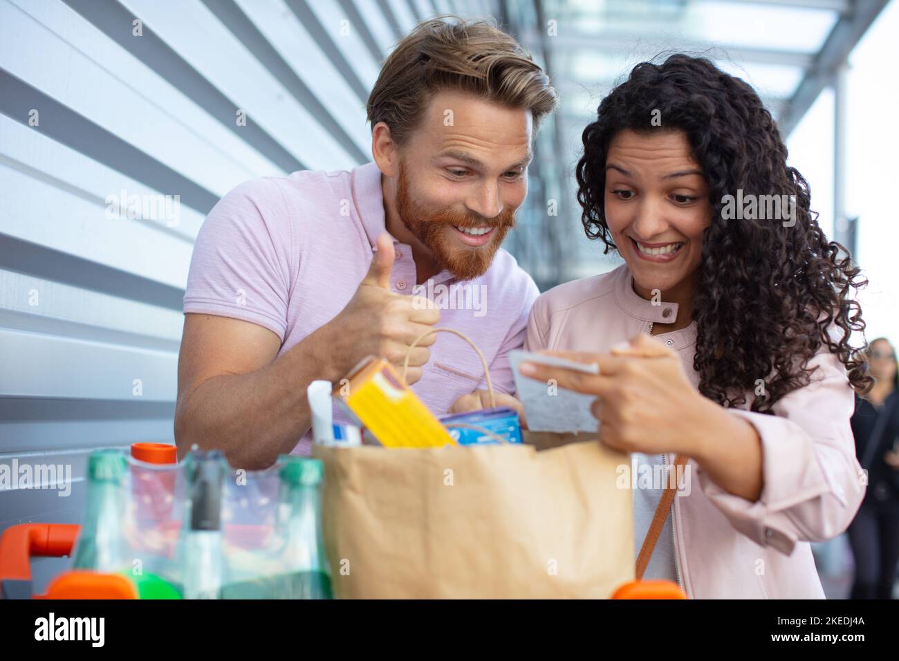 coppia soddisfatta che guarda la ricevuta di acquisto con i pollici-in su Foto Stock
