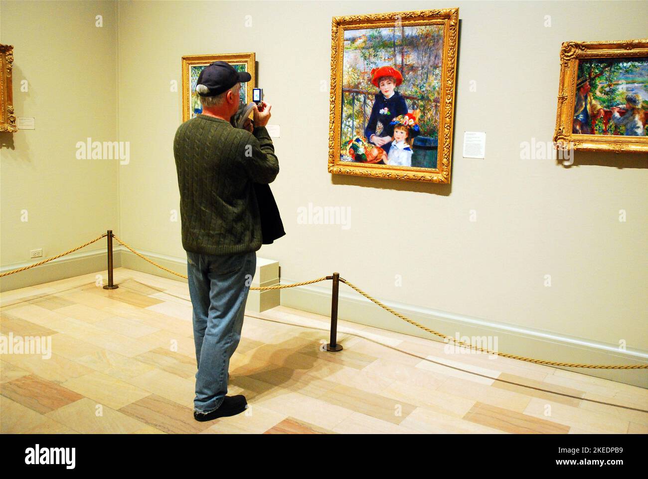 Un uomo adulto scatta una foto di Two Sisters on the Terrace, un dipinto di Pierre-Auguste Renoir, al museo Art Institute of Chicago Foto Stock