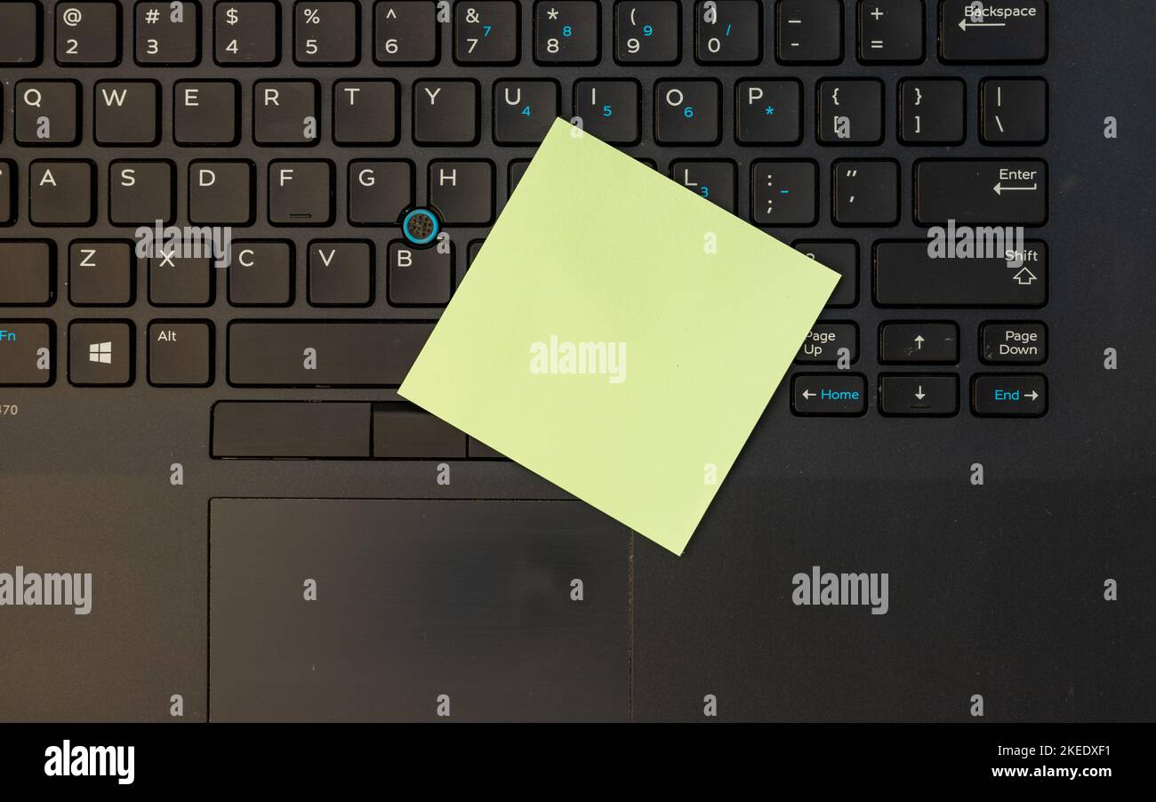 Nota adesiva vuota gialla sulla tastiera di un notebook con vista ad angolo alto Foto Stock