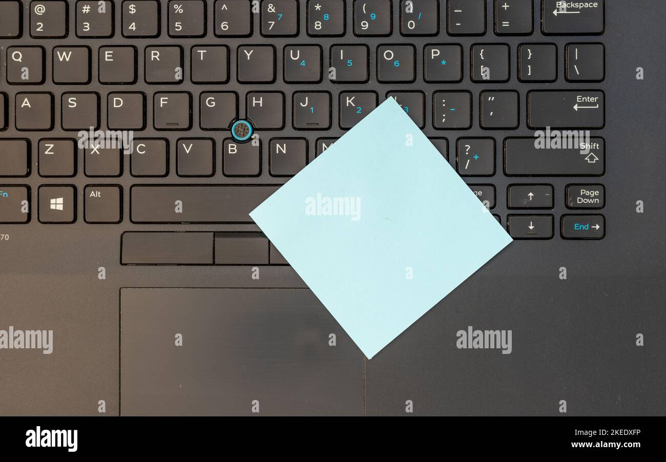 Tastiera del computer portatile con una nota adesiva vuota blu Foto Stock