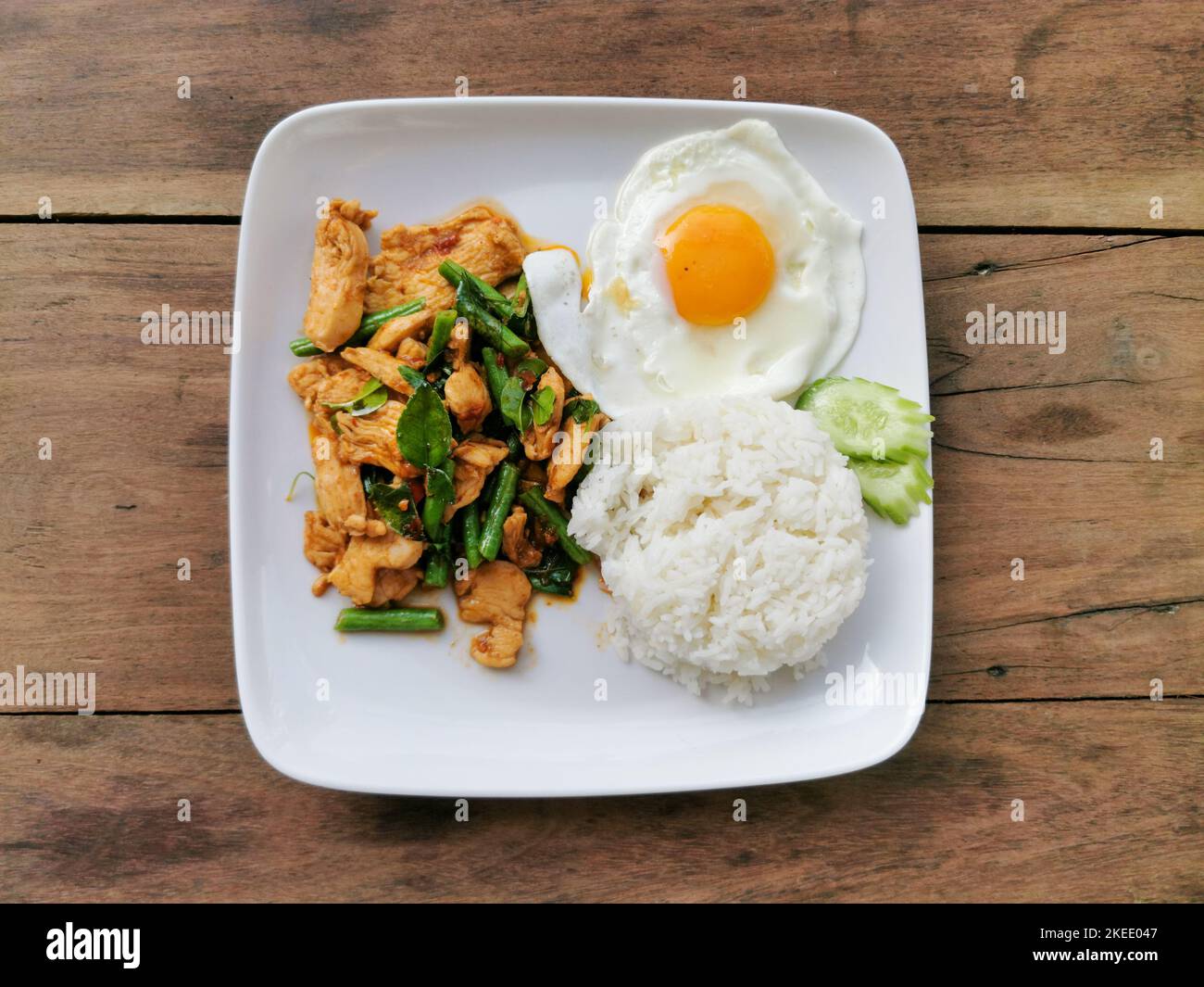Fettete il gaeng moo o mescolate il maiale al curry rosso fritto con riso bianco su un piatto bianco con fondo in legno. Cibo di strada tailandese in Thailandia. Foto Stock