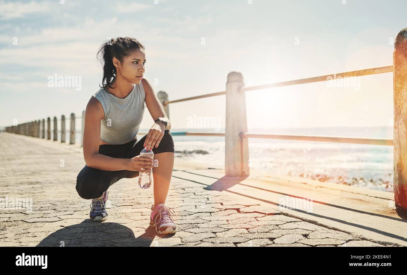 Una giovane donna sportiva che si accovacciava fuori. Foto Stock