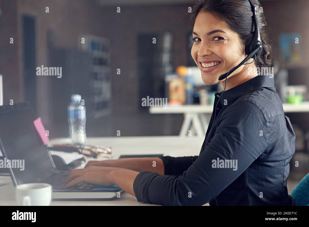 Al di là della chiamata. Un operatore del call center seduto alla sua scrivania in un ufficio moderno. Foto Stock