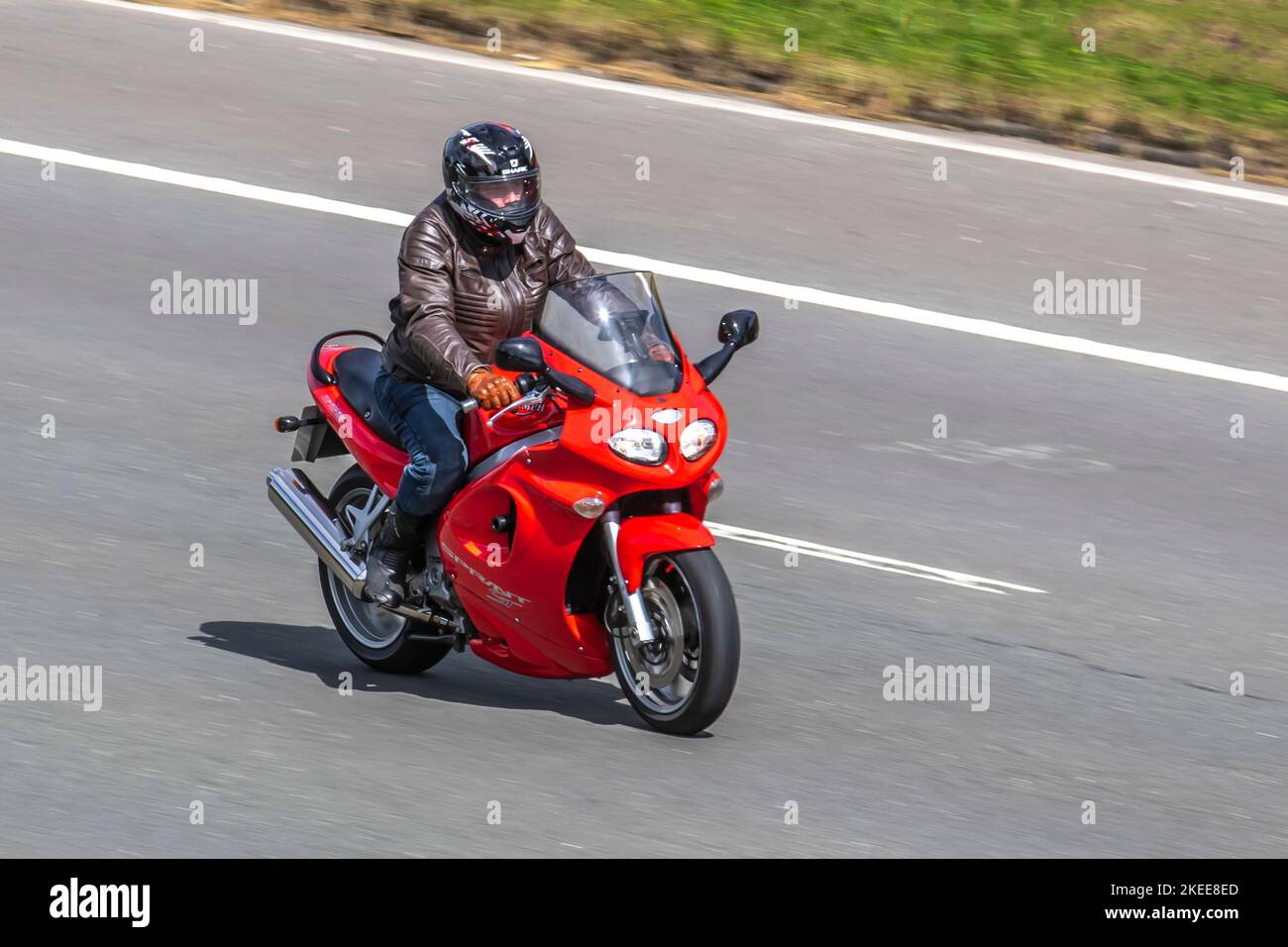 Red 955 Triumph ST Sprint motociclista con visiera giù viaggiando sull'autostrada M6 UK Foto Stock