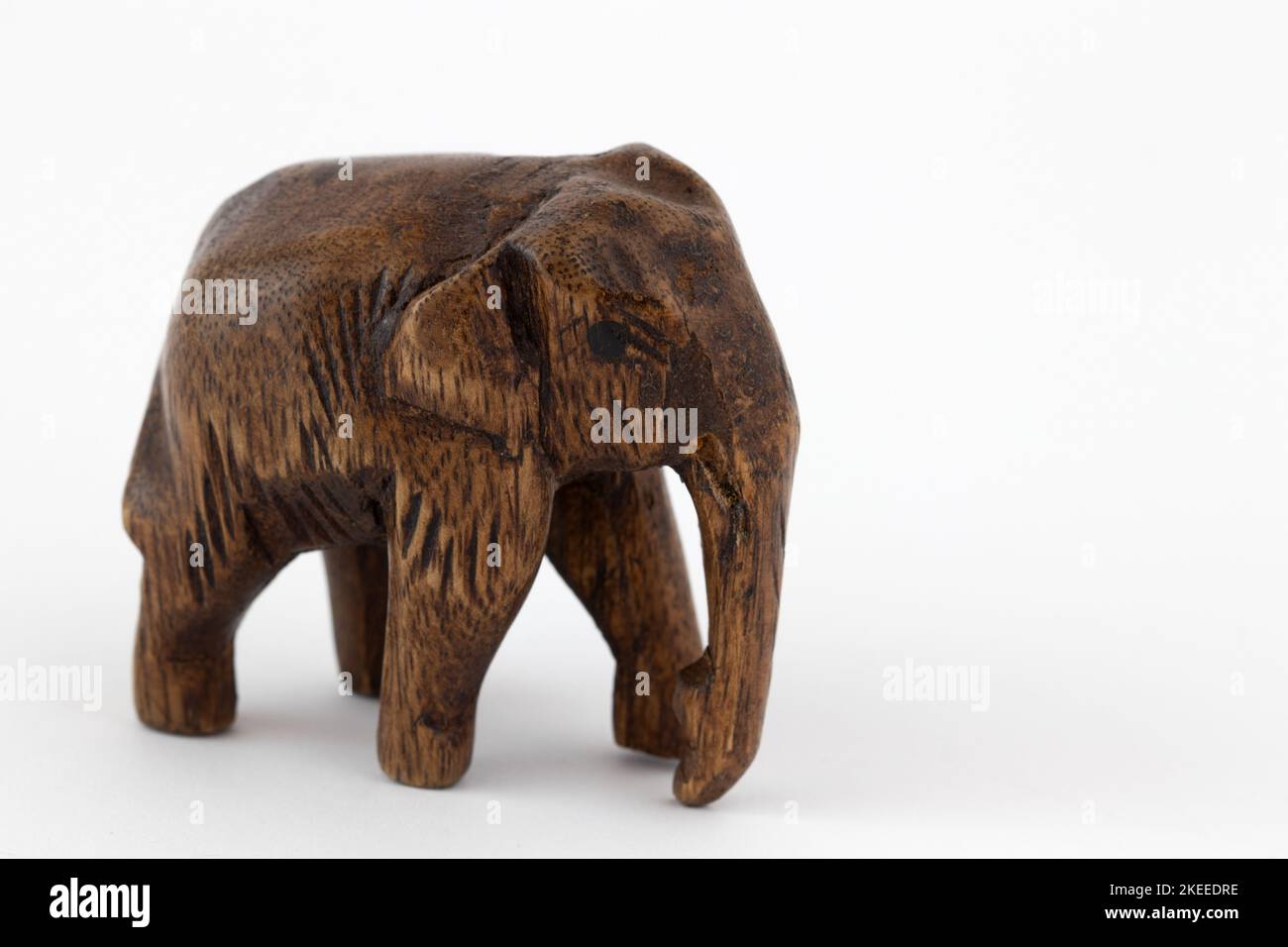 Una piccola statuetta di elefante di legno isolata su sfondo bianco Foto Stock