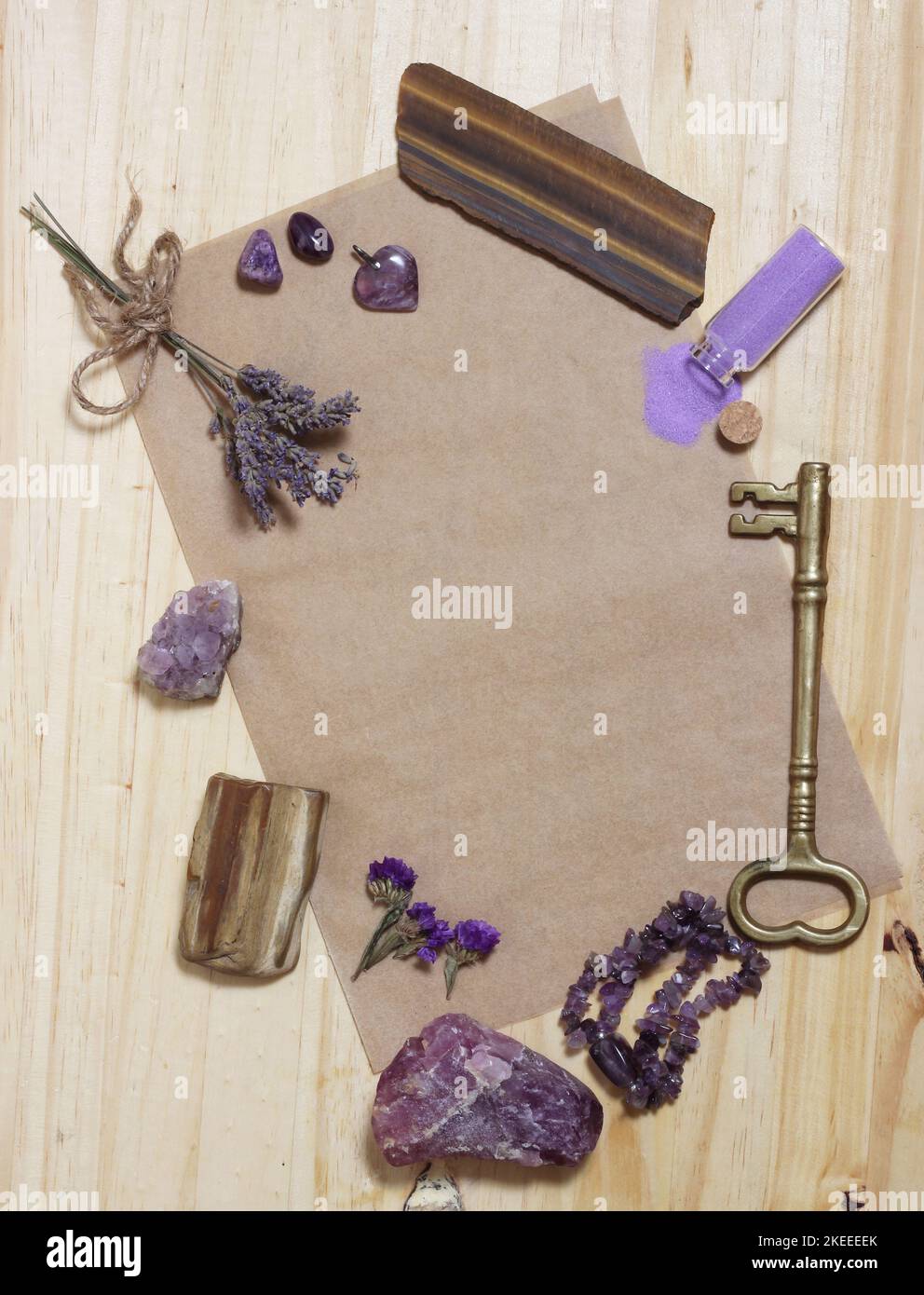 Pietre di Ametista con legno pietrificato su carta vecchia con fiori secchi. Sfondo del tema viola Foto Stock