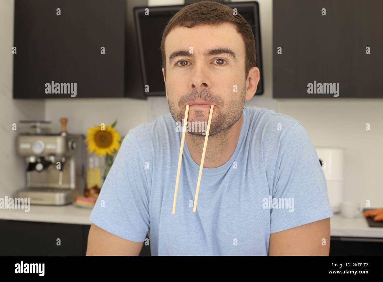 Uomo che fa faccia divertente con coppia di bacchette Foto Stock