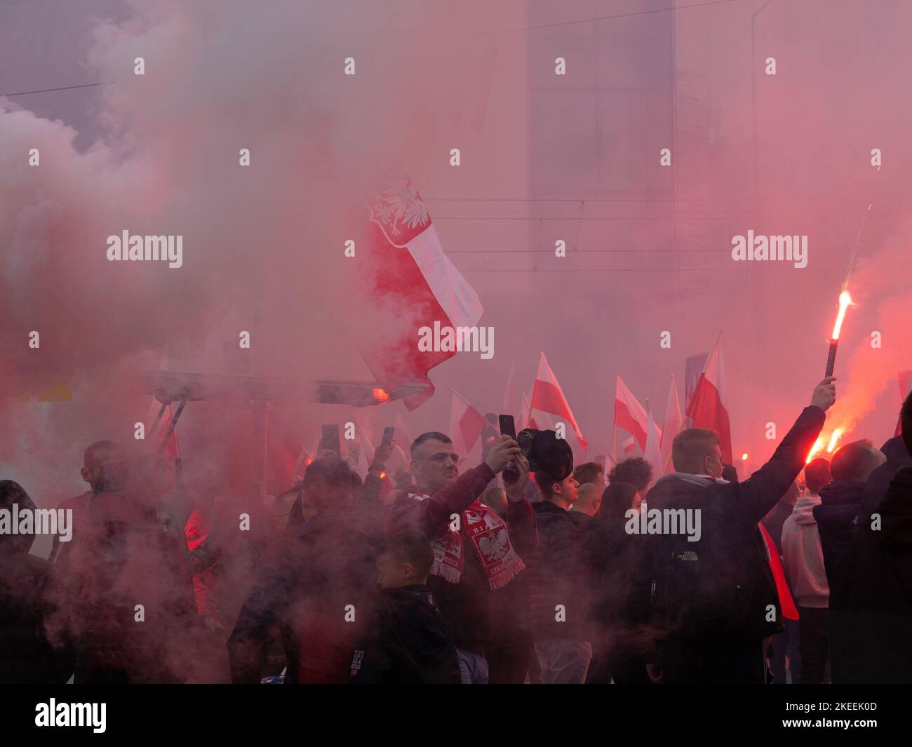 La gente celebra la Giornata dell'Indipendenza Polacca, 11 novembre. Folla con bandiere polacche avvolte nel fumo. Alcuni stanno tenendo i fares. Foto Stock